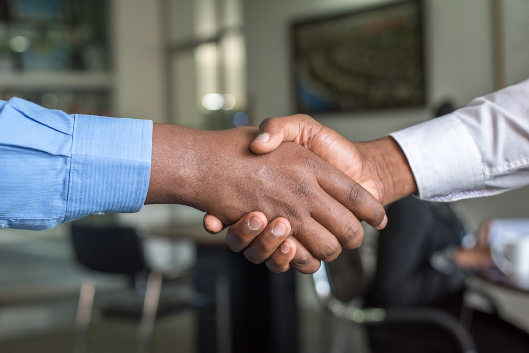 Two people shaking hands across a desk